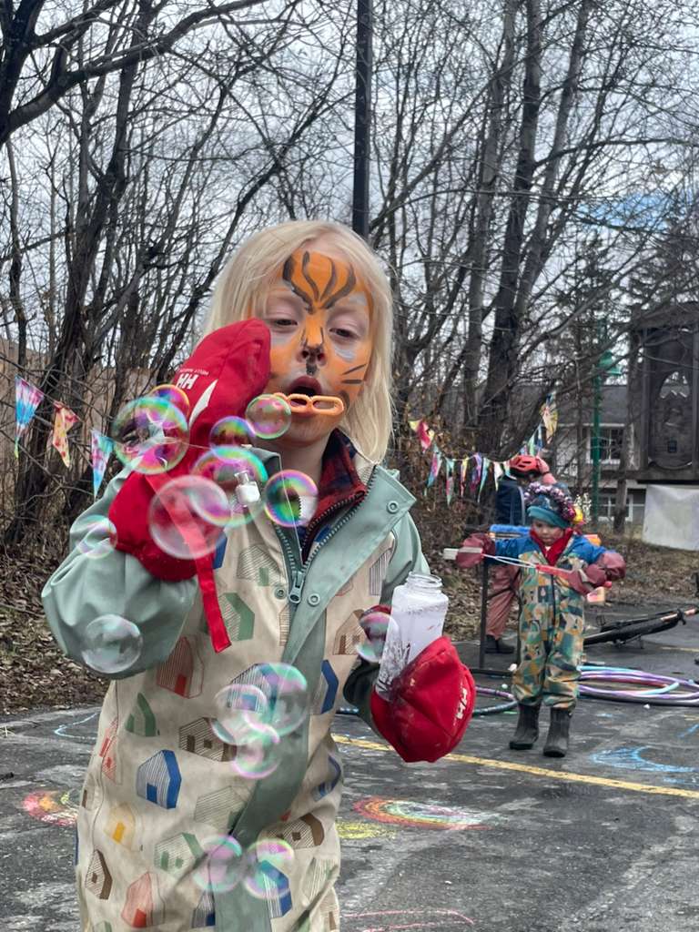 student with tiger painted face blowing bubbles at the anchorage waldorf may faire